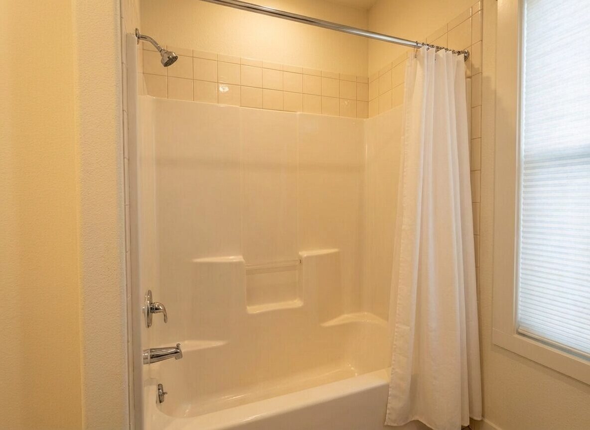 Dated bathroom with old tile and shower curtain before renovation