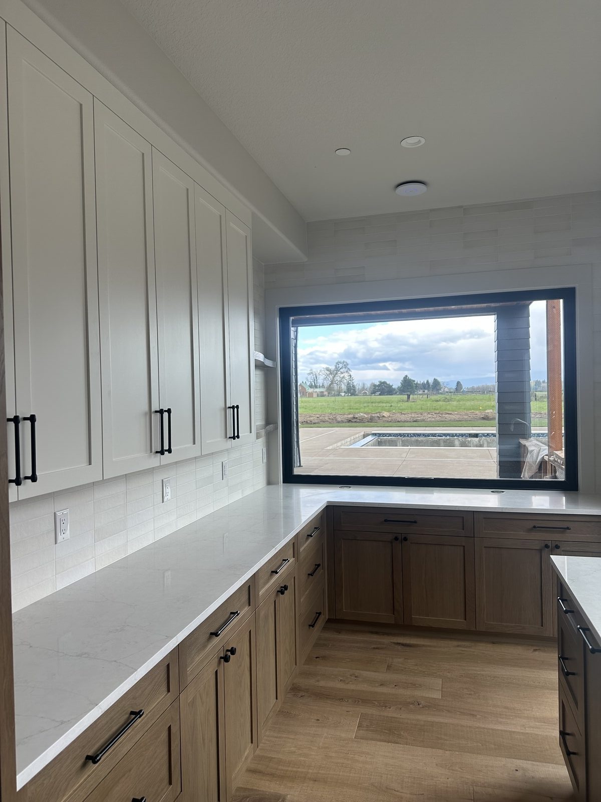 Kitchen with white countertops, tile backsplash, and two-tone cabinetry, installed by BM Pro Construction